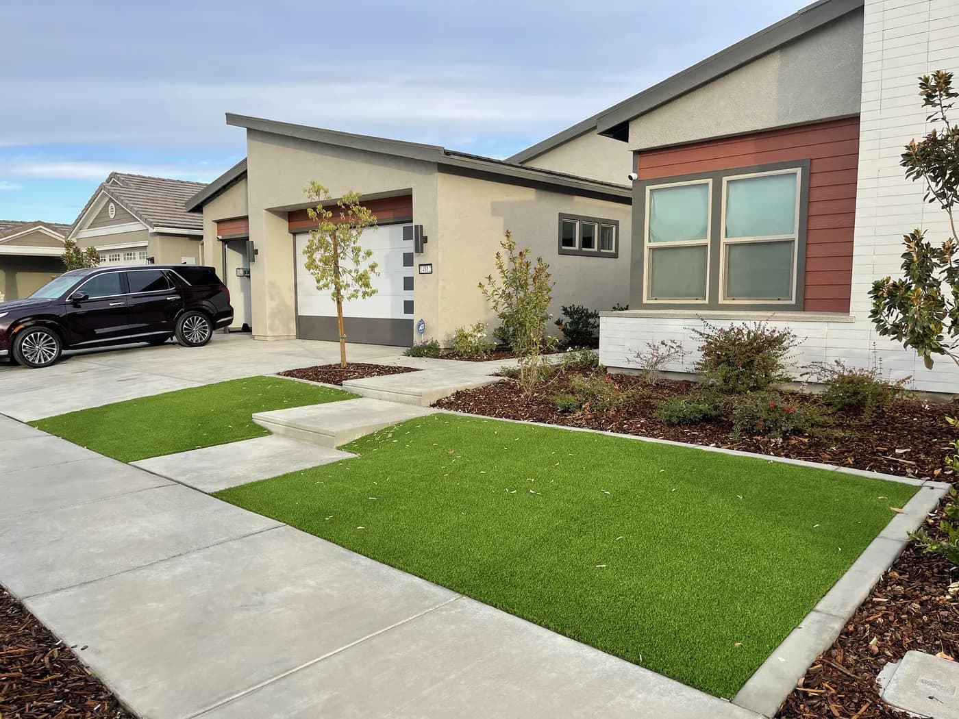 Artificial turf panels between concrete walkways in front of a modern home